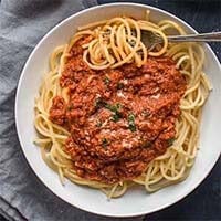 Instant Pot Sunday Gravy over noodles on a white plate with a fork