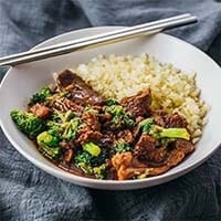 Instant Pot Beef and Broccoli with rice in a white bowl with chopsticks