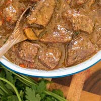 Pressure Cooker Beef Tips in a white bowl with a wooden spoon
