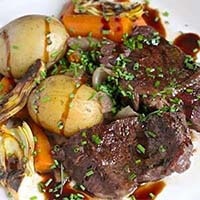 Braised Short Ribs with Vegetables and Artichoke Hearts on a white plate