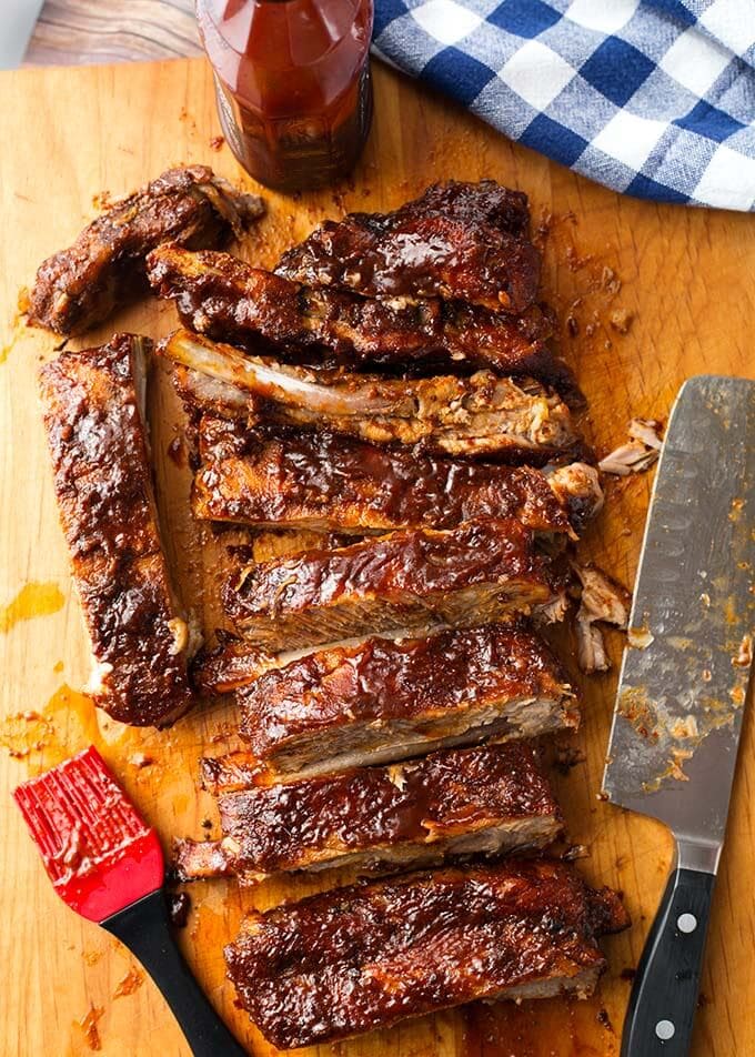 Sliced Instant Pot Baby Back Ribs on wooden board with meat cleaver and sauce brush