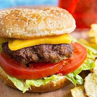 Hamburgers with cheese tomato, and lettuce on a board with potato chips