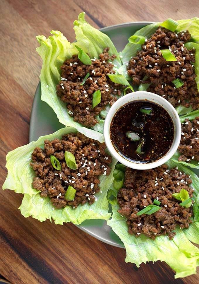 Korean Ground Beef on lettuce leaves with a small bowl of sauce in the middle of the plate