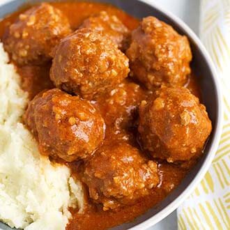 Porcupine Meatballs next to mashed potatoes in a white bowl