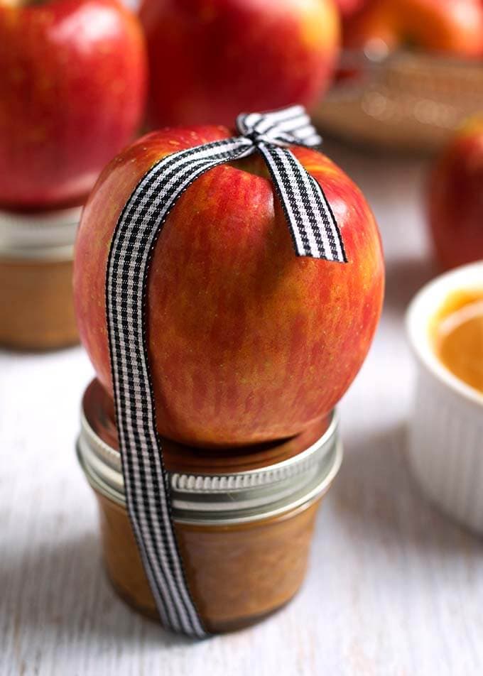 Small jar of Dulce de Leche Caramel with an apple on top tied together with a ribbon