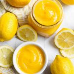 Lemon Curd in a small glass jar and white bowl, all surrounded by cut lemons