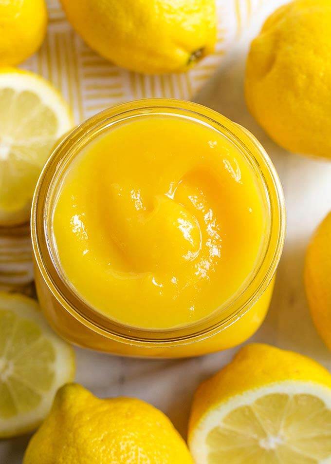 Top view of a small jar of Lemon Curd surrounded by cut lemons