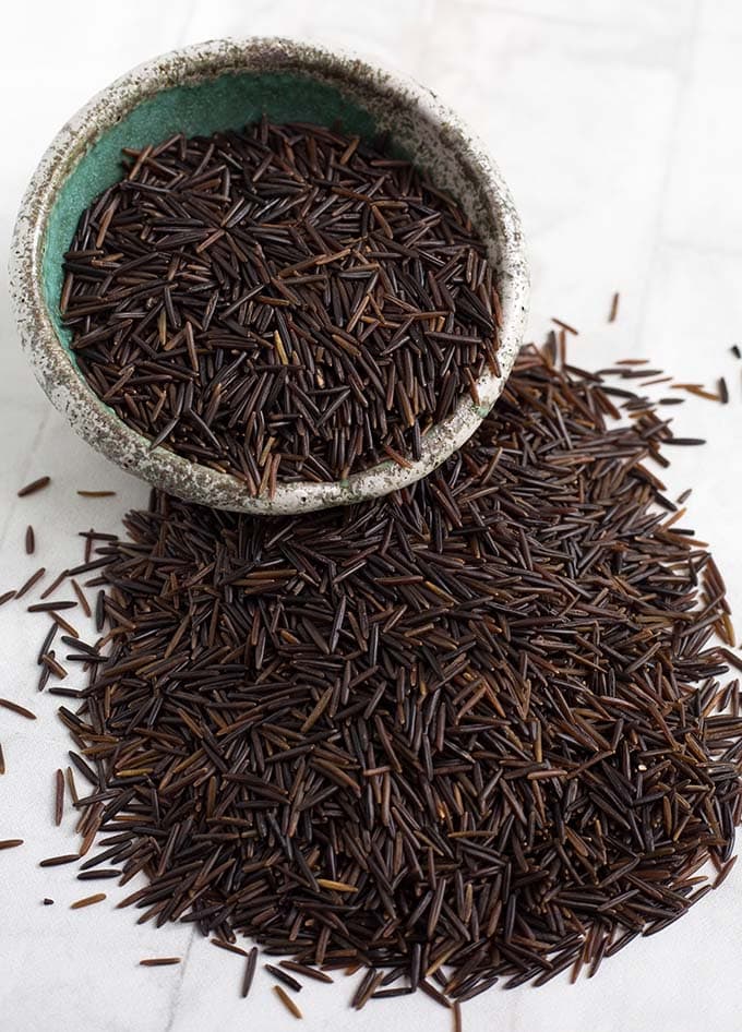 wild rice grains overflowing from small gray bowl