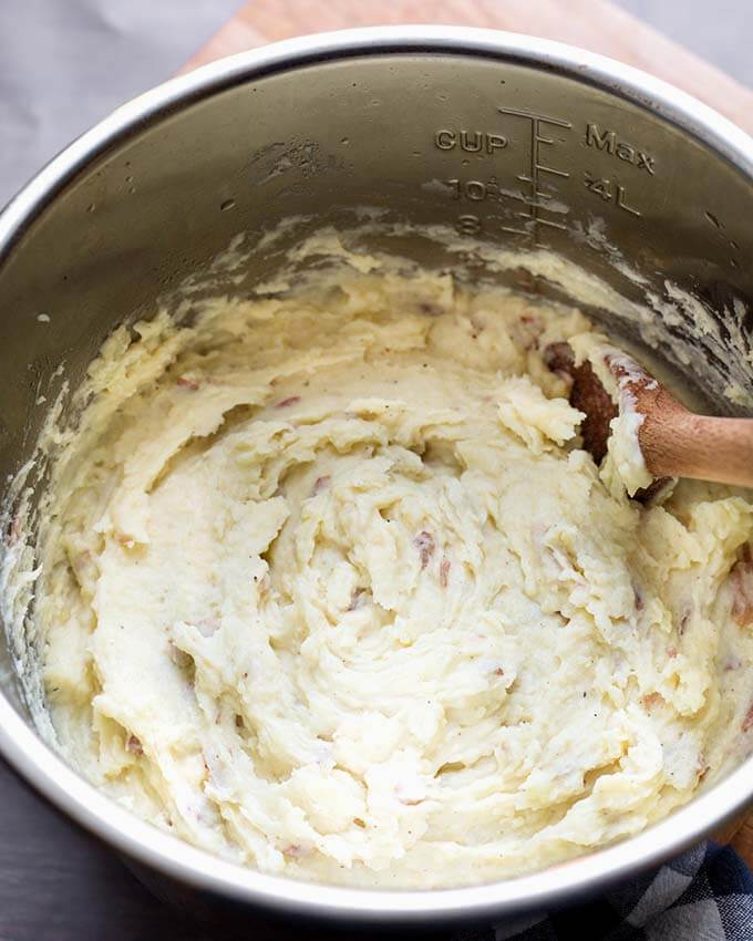 Top view of Creamy Mashed Potatoes in a pressure cooker pot with wooden mixing spoon