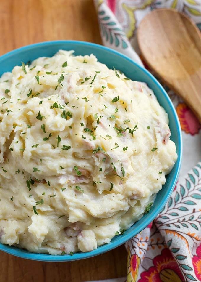 Closeup of Creamy Mashed Potatoes in a blue bowl on a wooden board