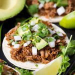 Barbacoa Beef on white corn tortillas topped with chopped avocados, onion and cilantro