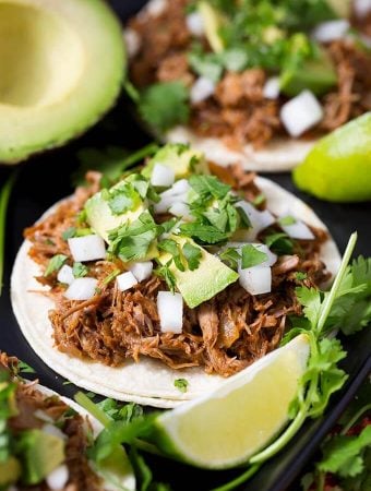 Barbacoa Beef on white corn tortillas topped with chopped avocados, onion and cilantro