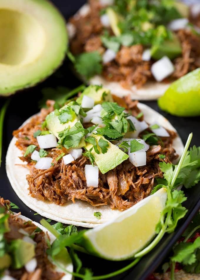 Barbacoa Beef on a white corn tortilla topped with diced avocado, onion, and cilantro