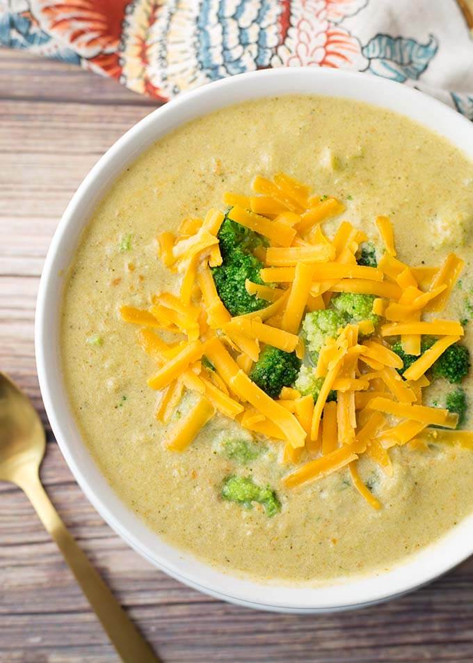 top view of Broccoli Cheddar Soup topped with shredded cheese and broccoli in a white bowl