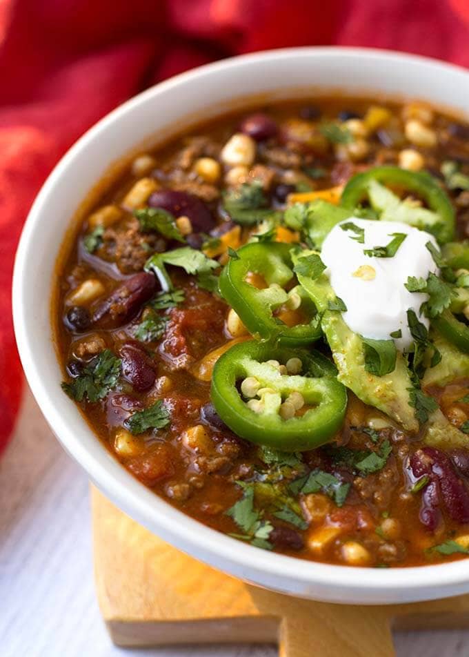 Closeup of Taco Soup topped with sliced jalapenos and sour cream in a white bowl