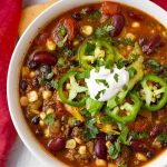 Taco Soup topped with sliced jalapenos and sour cream in a white bowl