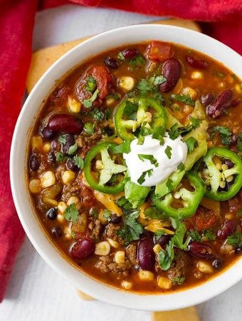 Taco Soup topped with sliced jalapenos and sour cream in a white bowl