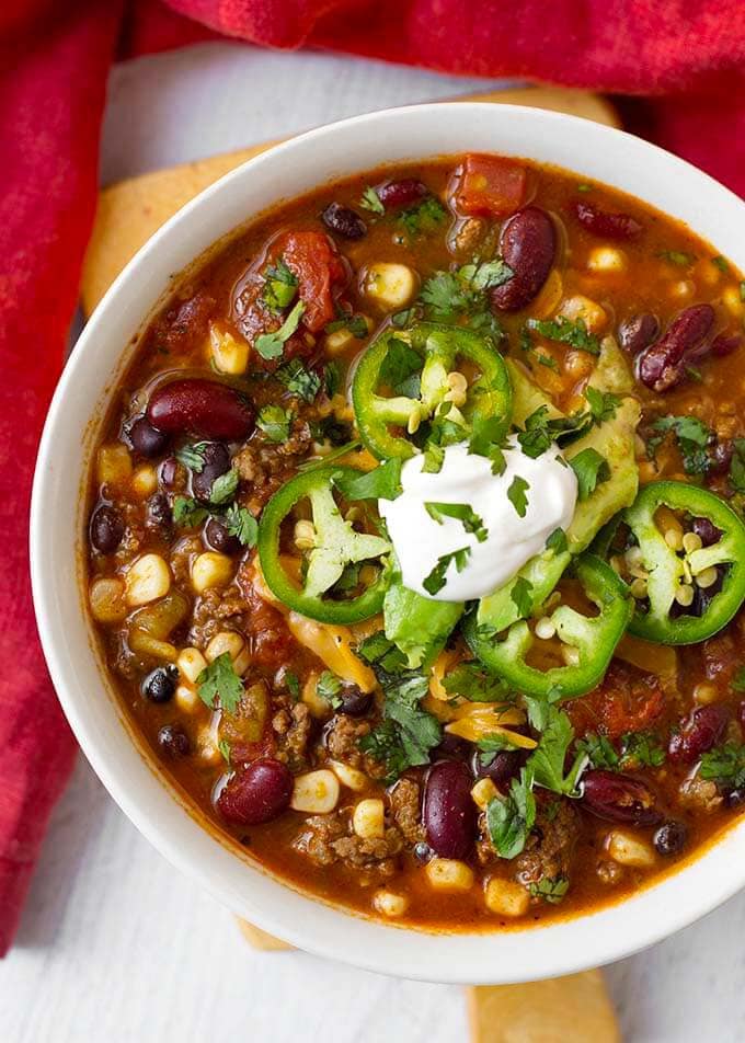 Taco Soup topped with sliced jalapenos and sour cream in a white bowl