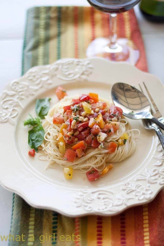 Fresh Tomato Summer Pasta Sauce over noodles on a white plate with a silver spoon and fork