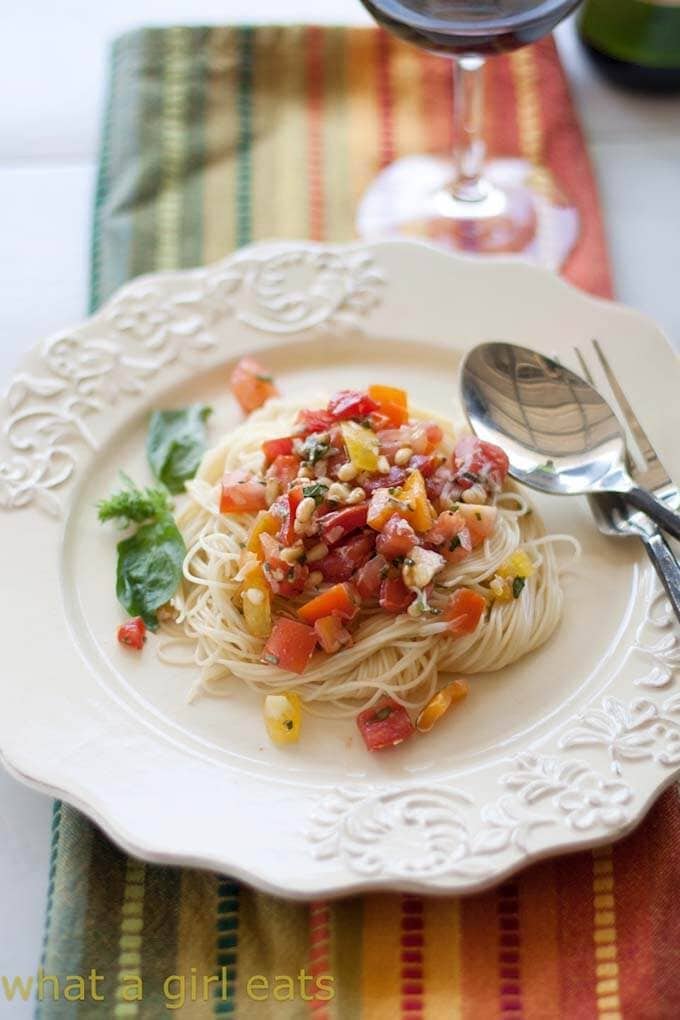 Fresh Tomato Summer Pasta Sauce over noodles on a white plate with a silver spoon and fork