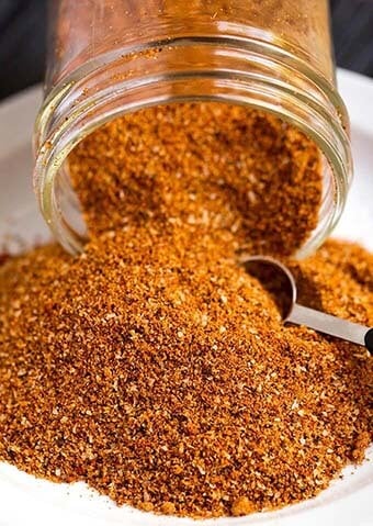 Ribs Spice Rub pouring out of a small glass jar