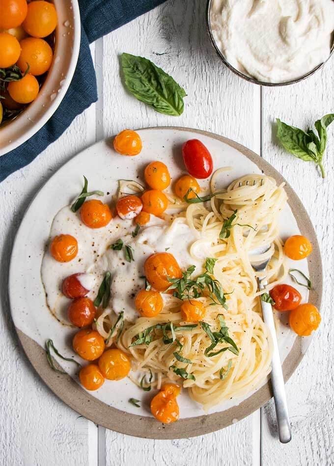 Summer tomato pasta on a weight and beige stoneware plate with silver fork