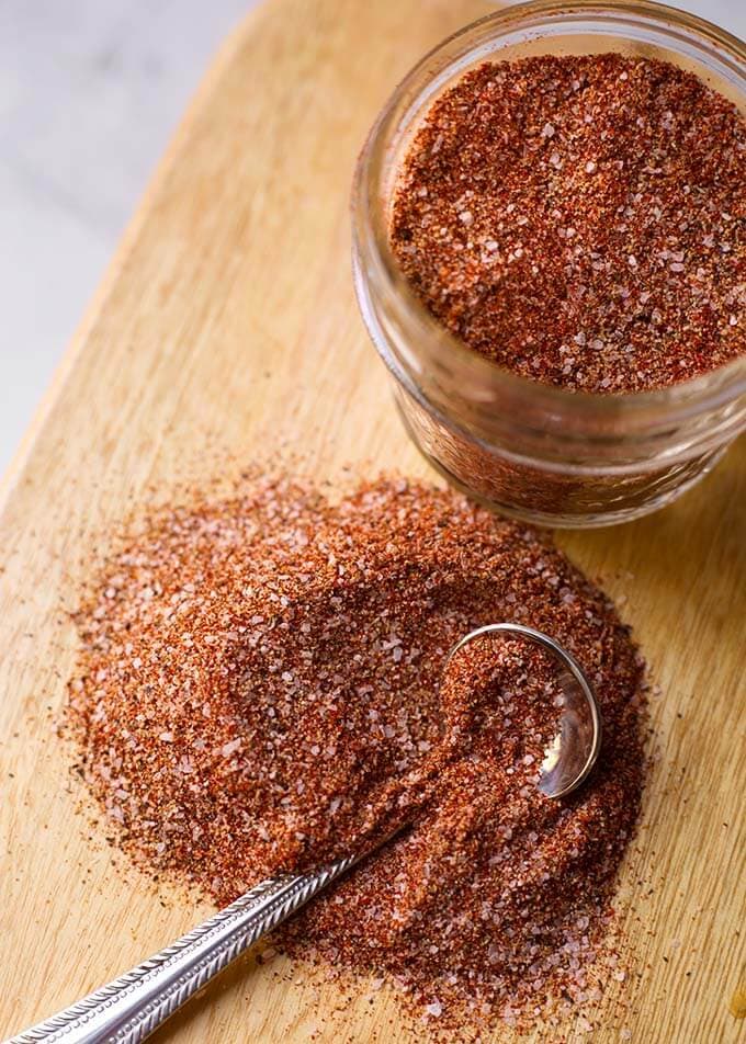 Baked chicken spice rub on a cutting board with a small teaspoon