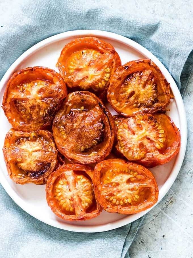 several cinnamon allspice baked tomatoes on a white plate