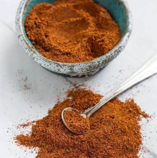 Homemade Fajita Seasoning in a turquoise stoneware bowl next to a pile of seasoning with a silver teaspoon