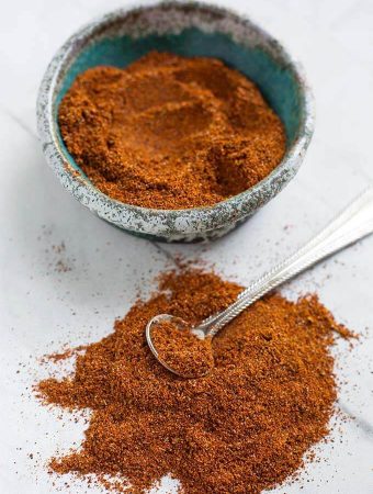 Homemade Fajita Seasoning in a turquoise stoneware bowl next to a pile of seasoning with a silver teaspoon