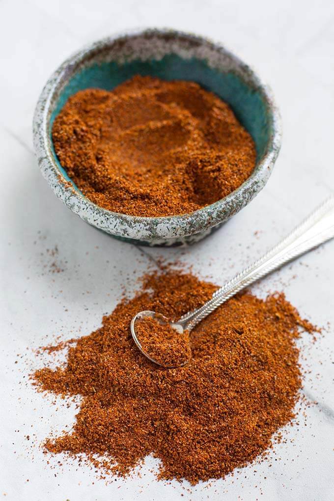 Homemade Fajita Seasoning in a turquoise stoneware bowl next to a pile of seasoning with a silver teaspoon