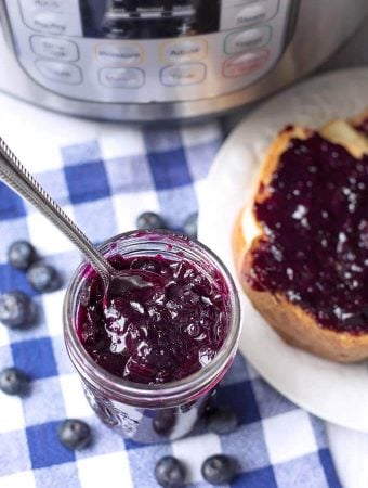 Blueberry Jam in a small glass jar with a silver spoon