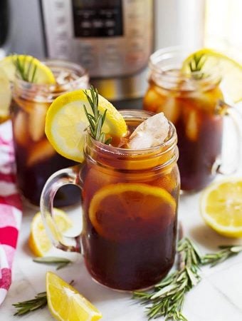 three glasses of iced tea on a table in front of a pressure cooker
