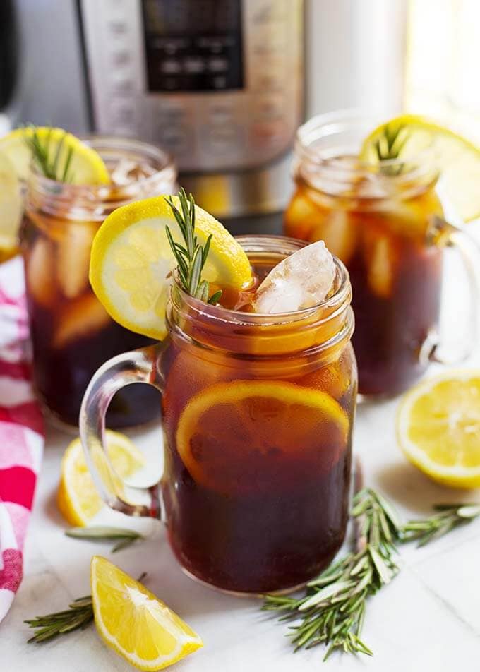 three glasses of iced tea on a table in front of a pressure cooker