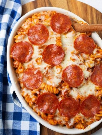 Pizza Pasta Casserole in a white oblong baking dish in front of a pressure cooker