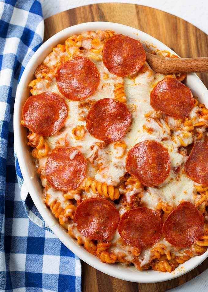 Pizza Pasta Casserole in a white oblong baking dish in front of a pressure cooker