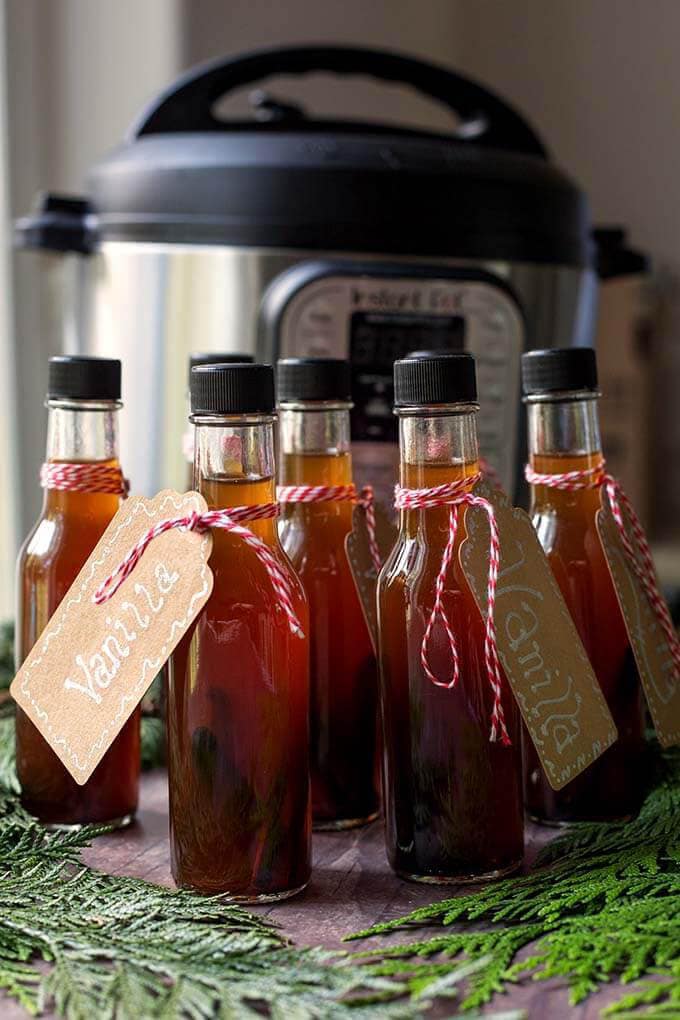 Several small bottles of Vanilla in front of a pressure cooker