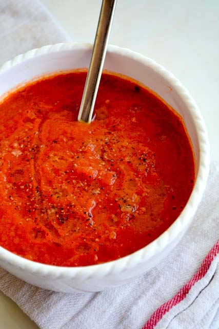roasted tomato soup in a white bowl with a spoon