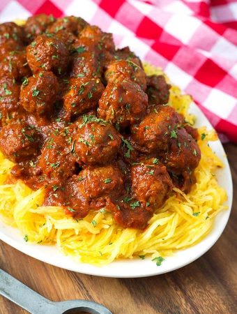 Spaghetti Squash and Meatballs on a white plate next to a red gingham napkin