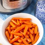 Cinnamon Glazed Carrots in a white bowl in front of a pressure cooker