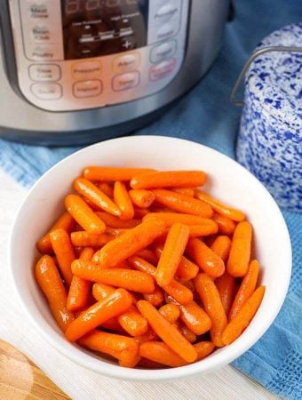 Cinnamon Glazed Carrots in a white bowl in front of a pressure cooker