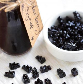 Elderberry gummy bears next to a small bottle of elderberry syrup