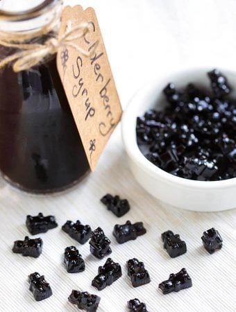 Elderberry gummy bears next to a small bottle of elderberry syrup