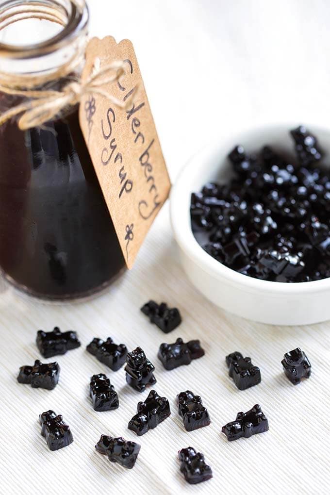 Elderberry gummy bears next to a small bottle of elderberry syrup