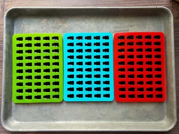 Three bear candy molds filled with elderberry gummy mixture sitting on a baking sheet