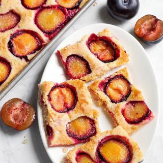 Fresh Plum Cake, also called Pflaumenkuchen and Zwetschgenkuchen (German Plum Cake) is a thin sheet cake baked with fresh plum slices on it. This Fresh Plum Cake recipe is simple, and not too sweet. A great way to use your fresh ripe plums! simplyhappyfoodie.com #freshplumcake #Pflaumenkuchen #Zwetschgenkuchen