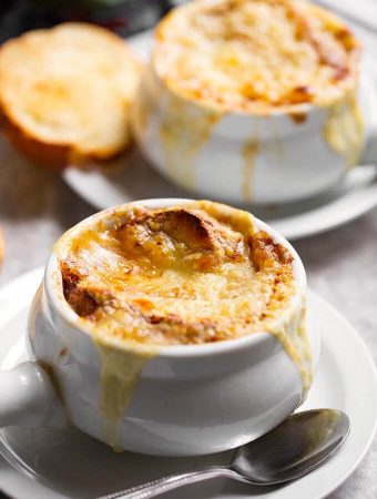 French Onion Soup with melted cheese and small slice of toasted bread on white plates