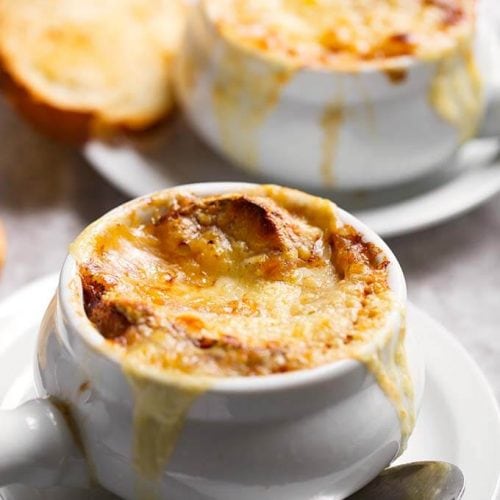 French Onion Soup with melted cheese and small slice of toasted bread on white plates