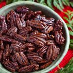 Maple Candied Pecans in a green bowl next to greenery