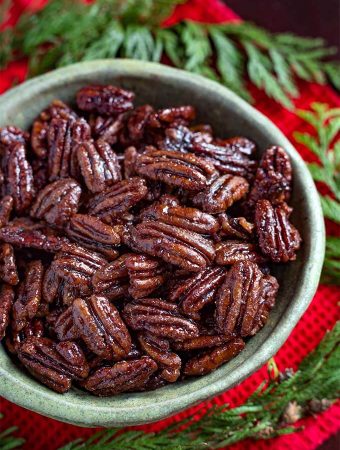 Maple Candied Pecans in a green bowl next to greenery